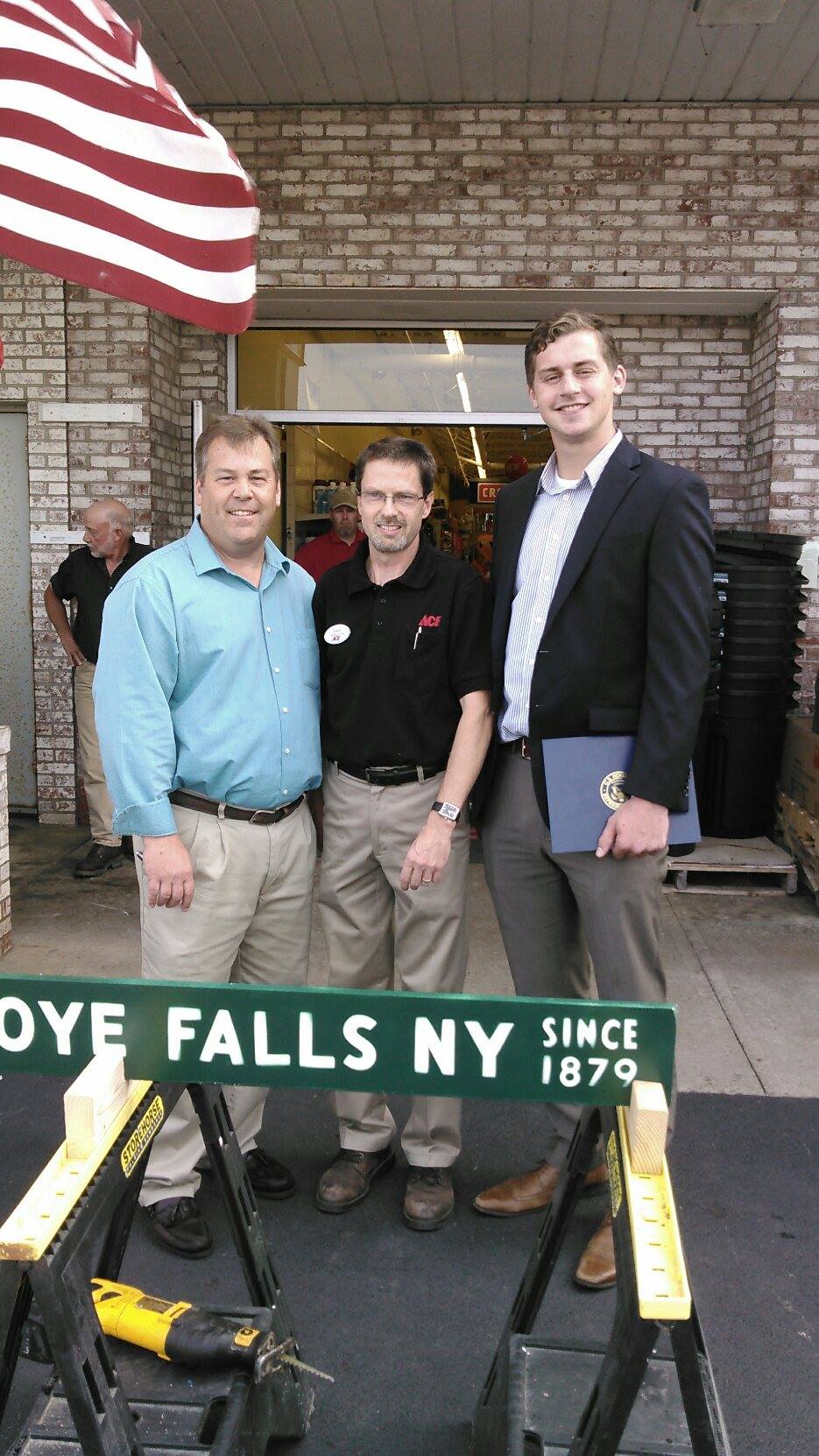 Ned Green and two other men posing in front of the Weider's Ace Hardware in Honeoye Falls after the board cutting ceremony