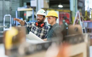 Two men wearing hardhats looking at building plans.