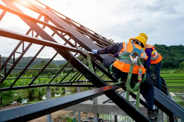 Workers wearing safety gear and harnesses working on a roof of a building.